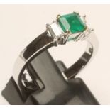 AN EMERALD AND DIAMOND THREE STONE RING, the square cut emerald claw set and flanked by two baguette