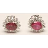 A PAIR OF RUBY AND DIAMOND CLUSTER EAR STUDS, the oval cut rubies claw set to a border of prong