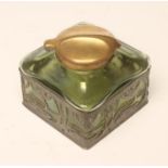 AN ART NOUVEAU INKWELL, c.1900, the rounded square green iridescent glass well with sloping