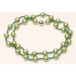 A SINGLE STRAND OF CULTURED PEARLS, the green stained pearls with small faceted emerald bead