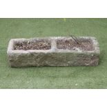 A SANDSTONE TROUGH of rough hewn oblong form with central division, 40 1/2" x 13 1/2" x 9 1/2" (Est.