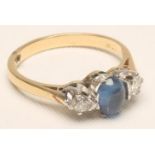 A SAPPHIRE AND DIAMOND THREE STONE RING, the central oval cabochon polished sapphire flanked by