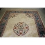 A CHINESE WASHED AND FRINGED CARPET, modern, the ivory field with central stylised floral roundel