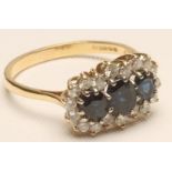 A SAPPHIRE AND DIAMOND TRIPLE CLUSTER RING, the three oval facet cut sapphires within a border of