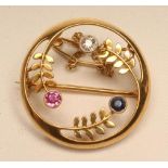 A 15CT GOLD BROOCH, the open circle enclosing three leafy fronds set with a small diamond, ruby