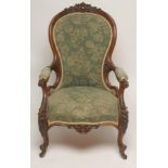 A VICTORIAN WALNUT FRAMED ARMCHAIR of spoonback form upholstered in green cut moquette, the