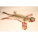 A SNOW LEOPARD SKIN RUG, with snarling head, glass eyes, mounted on cloth with a red felt edging,