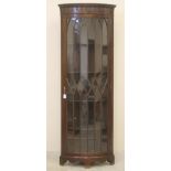 A MAHOGANY STANDING CORNER CUPBOARD, early 20th century, of bowed form with stringing, moulded