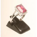 A RUBY AND DIAMOND RING, the emerald cut ruby of approximately 4.65cts claw set to a border of