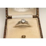 A DIAMOND RING, the central brilliant cut stone of approximately 0.20cts flanked by a pair of