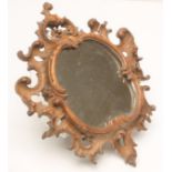 A CARVED LIMEWOOD WALL MIRROR, 19th century, possibly earlier, the later oval plate within a