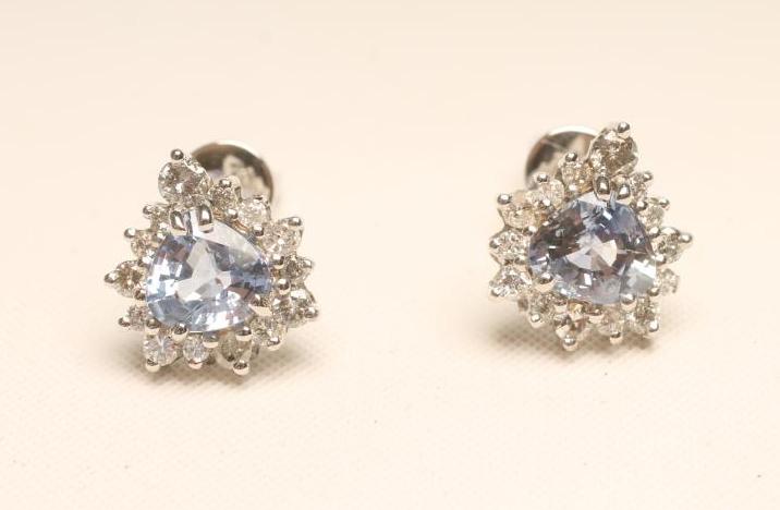 A PAIR OF SAPPHIRE AND DIAMOND EAR STUDS, the pear cut sapphires claw set to a border of fourteen
