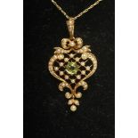 AN EDWARDIAN 15CT GOLD PENDANT, the bow tied cartouche centred by a facet cut peridot on a seed