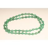 A SINGLE STRING OF AUSTRALIAN JADE BEADS, the fifty six faceted beads with facet cut emerald