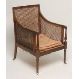 A REGENCY MAHOGANY BERGERE, the channelled frame with straight top rail, downward sloping arms on