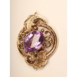 A LARGE VICTORIAN BROOCH, centred by an open back collet set amethyst in an oval scroll open mount