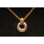 A GARRARD 18CT GOLD PENDANT AND CHAIN, the white gold open roundel applied with a yellow gold crown,