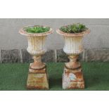 A PAIR OF CAST IRON URNS, c.1900, of fluted campana form on waisted socle and square base, raised on