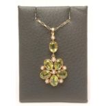 A PERIDOT FLOWER PENDANT, the five oval facet cut petals interspersed with seed pearls and hung from