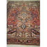 A PERSIAN WOOL CARPET, 20th century, the red floral field with large central star shaped gul and