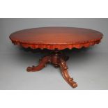 A VICTORIAN WALNUT LOO TABLE, the moulded edged tip up top and waved frieze raised on lobed