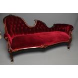 A VICTORIAN WALNUT FRAMED CHAISE LONGUE, button upholstered in red velvet, the padded back with