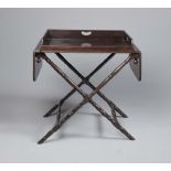 A BUTLER'S REGENCY MAHOGANY TRAY ON STAND, the oblong tray with three quarter gallery and cut away