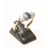 A SAPPHIRE AND DIAMOND THREE STONE RING, the central facet cut sapphire claw set and flanked by