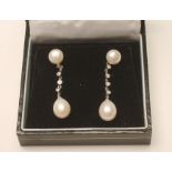 A PAIR OF PEARL AND DIAMOND DROP EAR STUDS, the tear shaped pearl drilled and pendant from four open