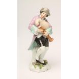 A SAMSON PORCELAIN FIGURE, late 19th century, of a young male bagpipe player wearing a grey hat