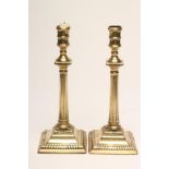 A PAIR OF GEORGIAN BRASS SEAMED CANDLESTICKS, late 18th century, the turned nozzle on fluted column,