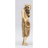 A JAPANESE IVORY NETSUKE, 18th century, carved as a fisherman, standing and holding a net in his