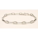 A DIAMOND BRACELET, the ten open oval panels point set with small stones and connected by 18kt white