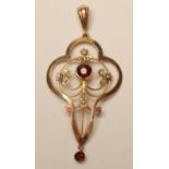 AN EDWARDIAN GARNET AND SEED PEARL PENDANT of oval quatrefoil form with wirework centre, 2 1/4" long