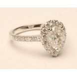 A DIAMOND CLUSTER RING, the central pear cut stone of approximately 1.68cts claw set to a border