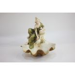 A Royal Dux porcelain figure (1860-1914) of a woman in green flowing dress collecting water from