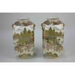 A pair of Japanese Satsuma vases depicting figures and dwellings beside a lake, with fo dog mask