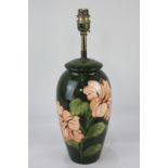 A Moorcroft pottery table lamp in the hibiscus pattern in peach on green ground, 38cm high