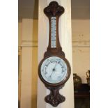 A 20th century aneroid wall barometer with thermometer, in carved oak banjo shaped case, 82cm