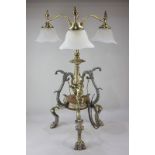 An unusual ornate gilt metal table lamp with three glass shaded lights, on central embossed stem