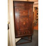 A Georgian oak corner cupboard with three shelves enclosed by panel door decorated with central