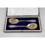 A matched pair of Edward VII silver serving spoons with shell shape bowl and decorative finials,