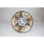 A Japanese Imari porcelain charger with scalloped rim, with panels decorated in rust, blue and gilt,