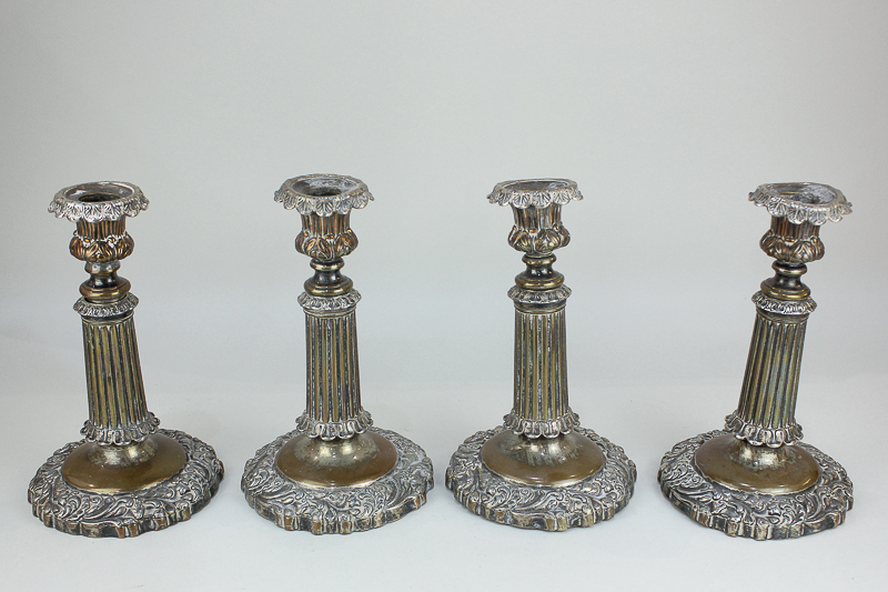 A set of four Sheffield silver plated candlesticks with foliate cast urn sconces, on fluted