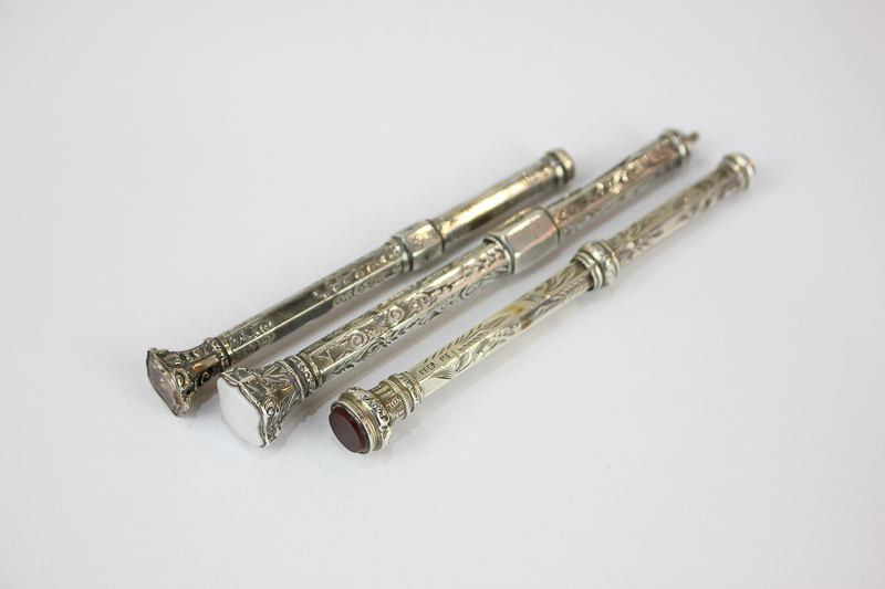 A Victorian silver propelling pencil with sliding action and hardstone seal, 4cm, and two similar