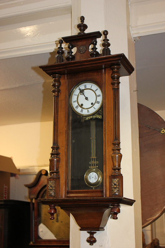 A Vienna style wall clock with circular white enamel dial, with brass pendulum, in glazed panel