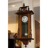 A Vienna style wall clock with circular white enamel dial, with brass pendulum, in glazed panel