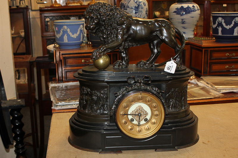 A Victorian black slate mantel clock with bronze lion and ball surmount, with relief figural