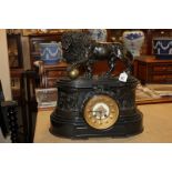 A Victorian black slate mantel clock with bronze lion and ball surmount, with relief figural