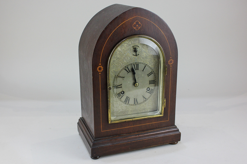 An Edwardian inlaid mahogany chiming mantel clock with silvered dial in arch shaped case, with